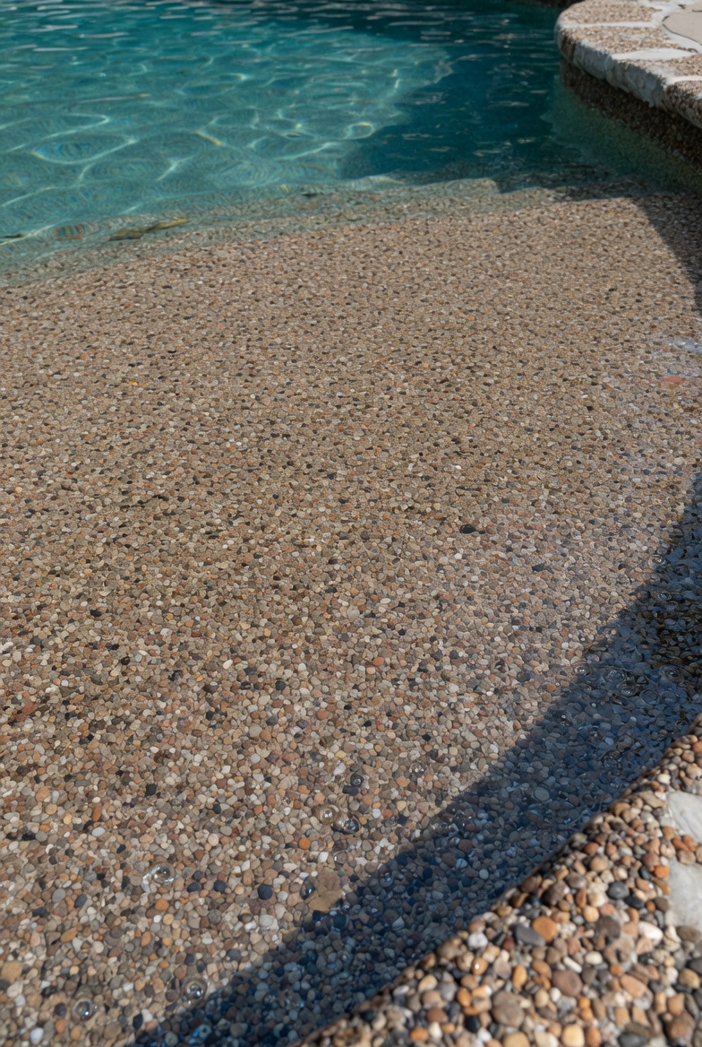 Close-up of a PebbleTec pool finish in St. George showing the natural pebble aggregate texture against clear blue water