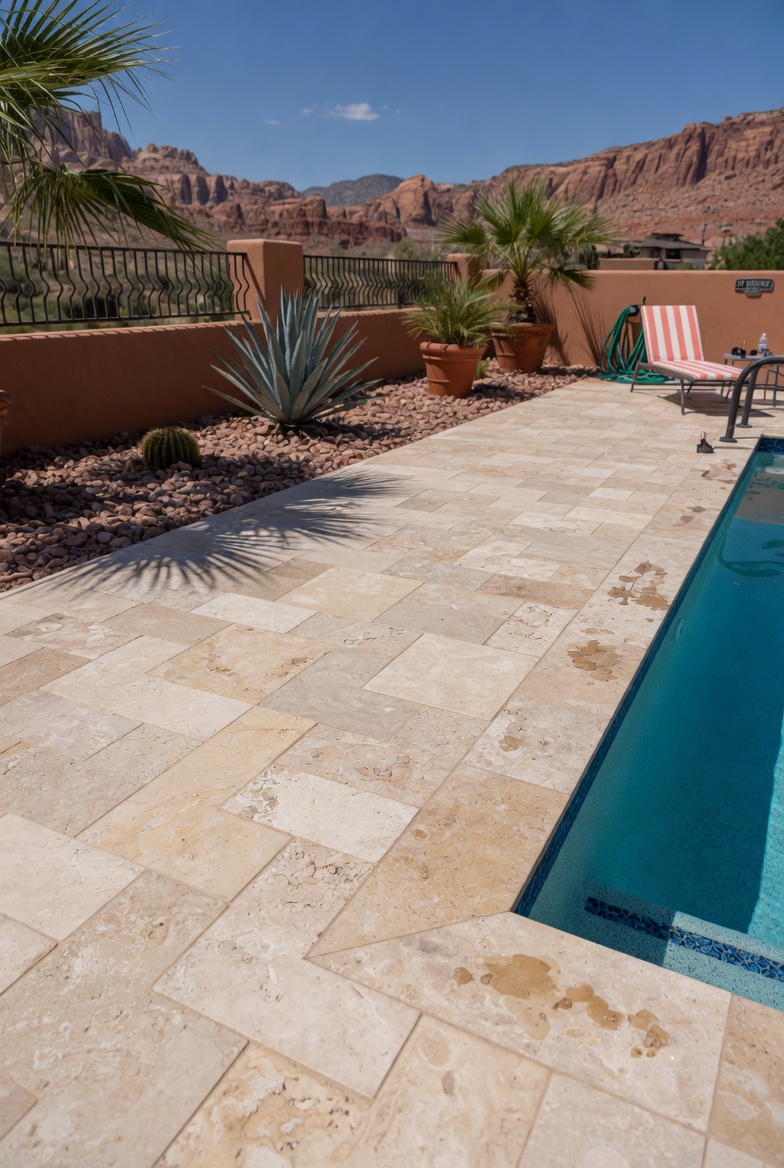 Travertine paver pool deck in St. George with red rock cliffs and desert landscaping in the background