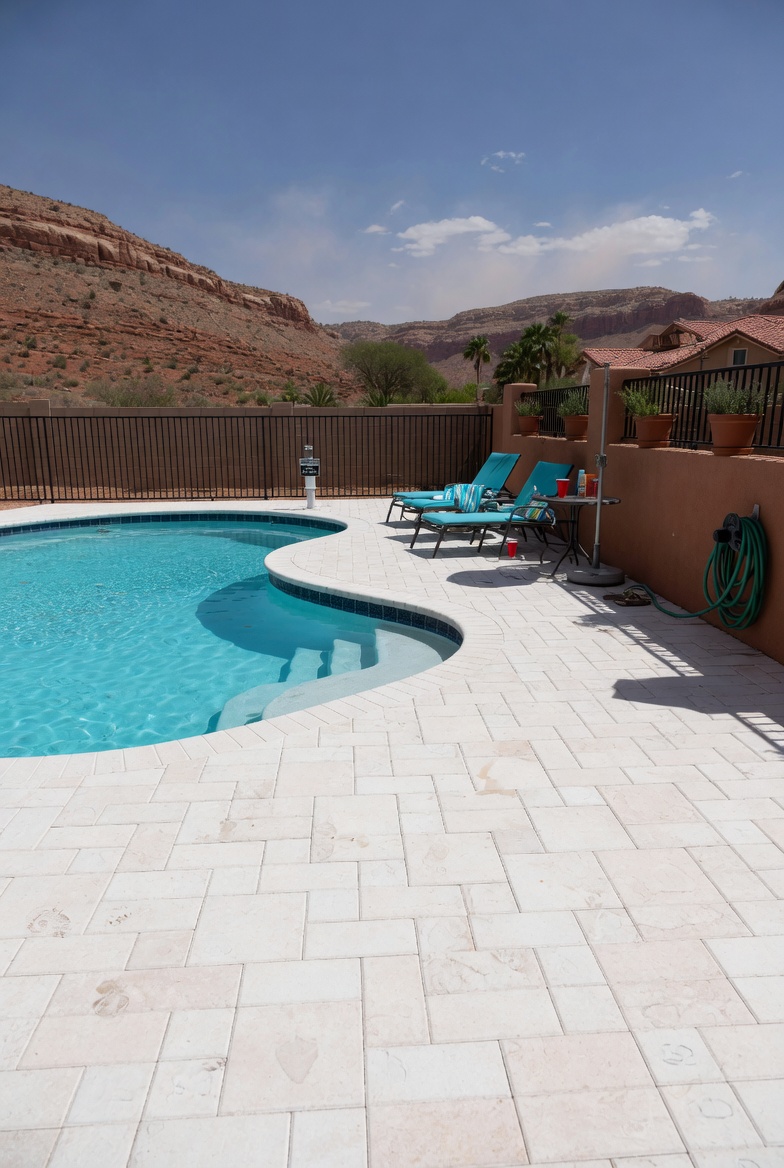 White concrete pavers around a St. George pool with red rock cliffs and mountain backdrop